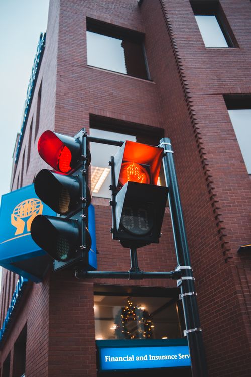 Free Low angle of red traffic lights against contemporary company facade with Christmas wreath behind window in town Stock Photo