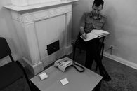 Focused policeman sitting on chair and writing in book