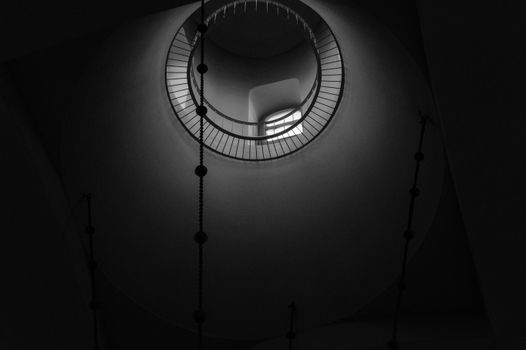 From below of high ceiling of dark accommodation with geometric niche with light from windows and chain ladder