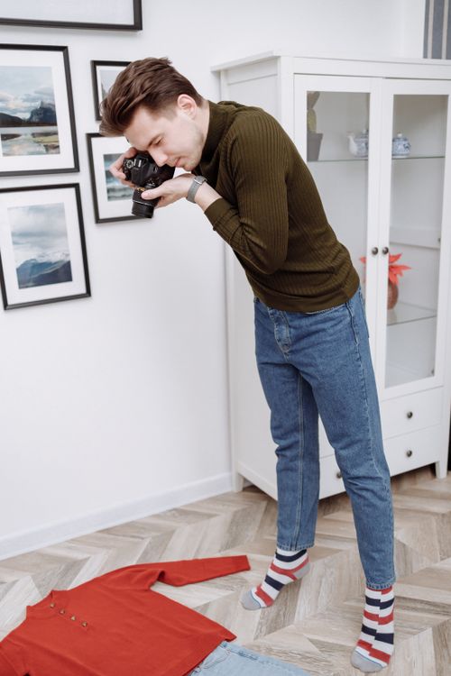 Free A photographer creatively captures a flat lay of clothing on the floor in a modern room. Stock Photo