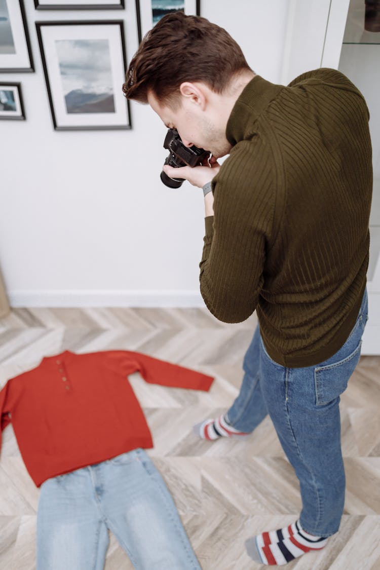 A Man In A Turtleneck Taking Pictures Of Clothes