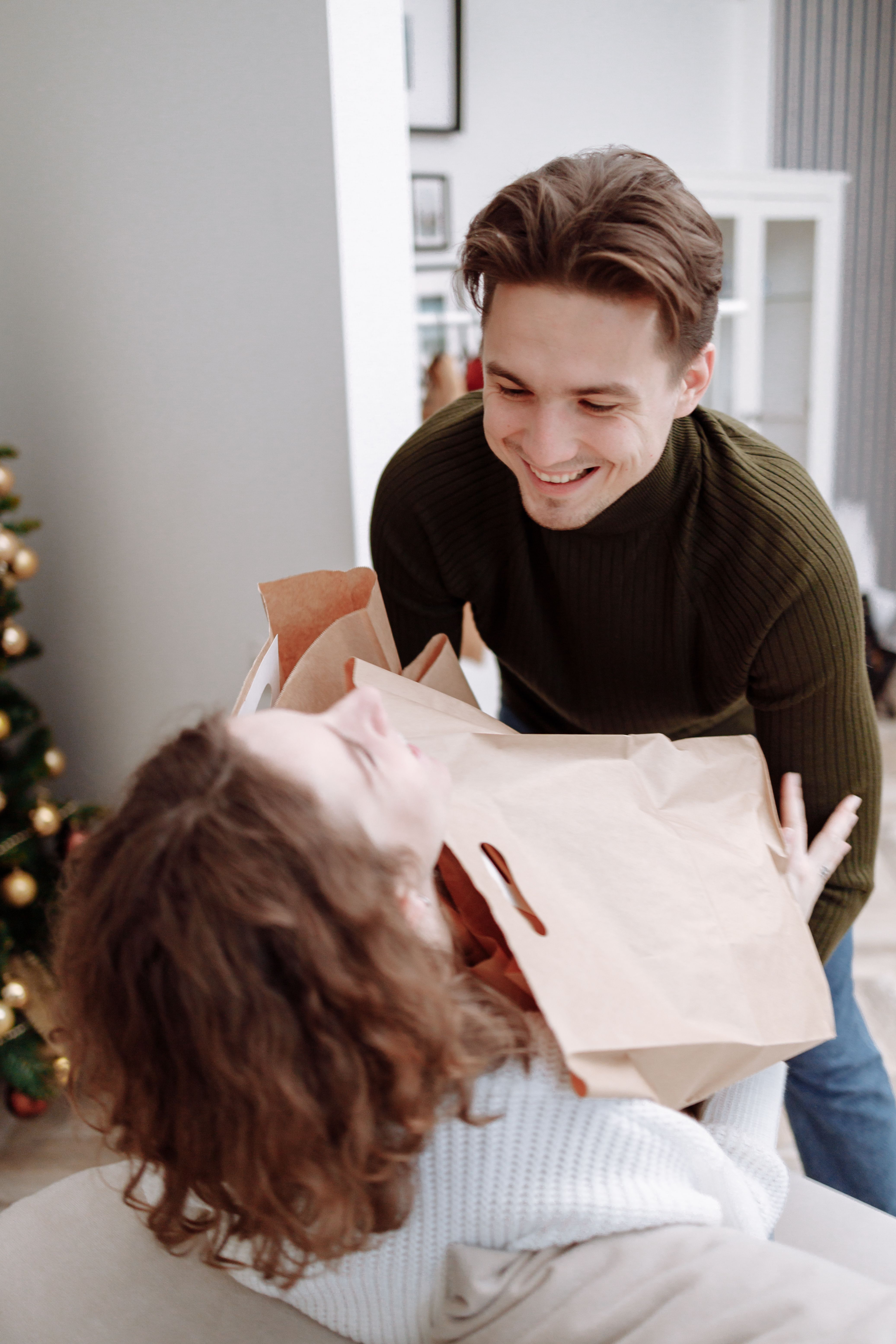 Happy couple enjoying holiday shopping indoors with paper bags.