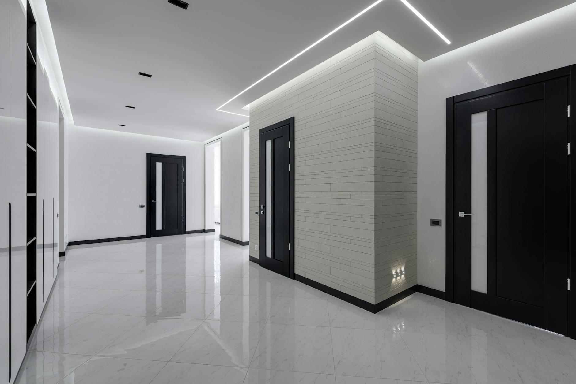 Modern spacious corridor with white walls and floor and black doors and ceiling decorated with LED lights