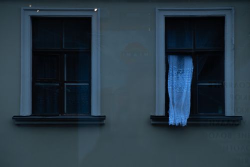 Free Sticking out contrast snow white curtain from window leaf near closed window on flat facade wall of building in twilight Stock Photo