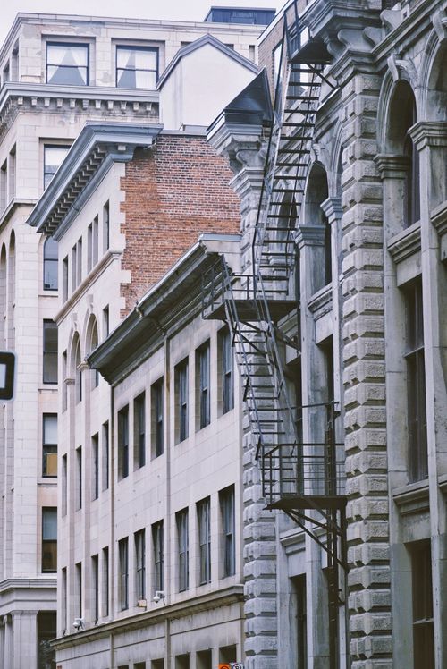 Free A vertical view of historic buildings in Montreal featuring classic fire escape designs and detailed masonry. Stock Photo