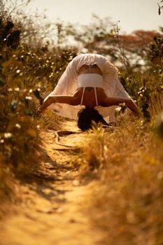 Full body of female practicing Wide Legged Forward Bend yoga posture during stress relief practice in sunny nature