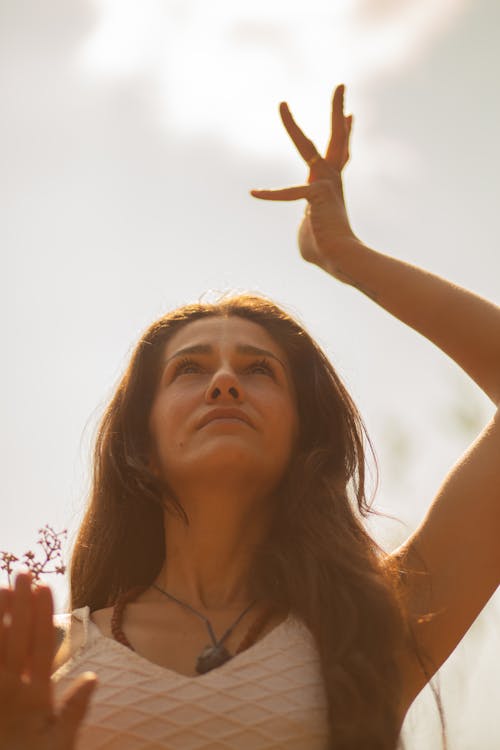 Free Low angle of graceful female with raised arm standing in nature and doing yoga while looking up Stock Photo