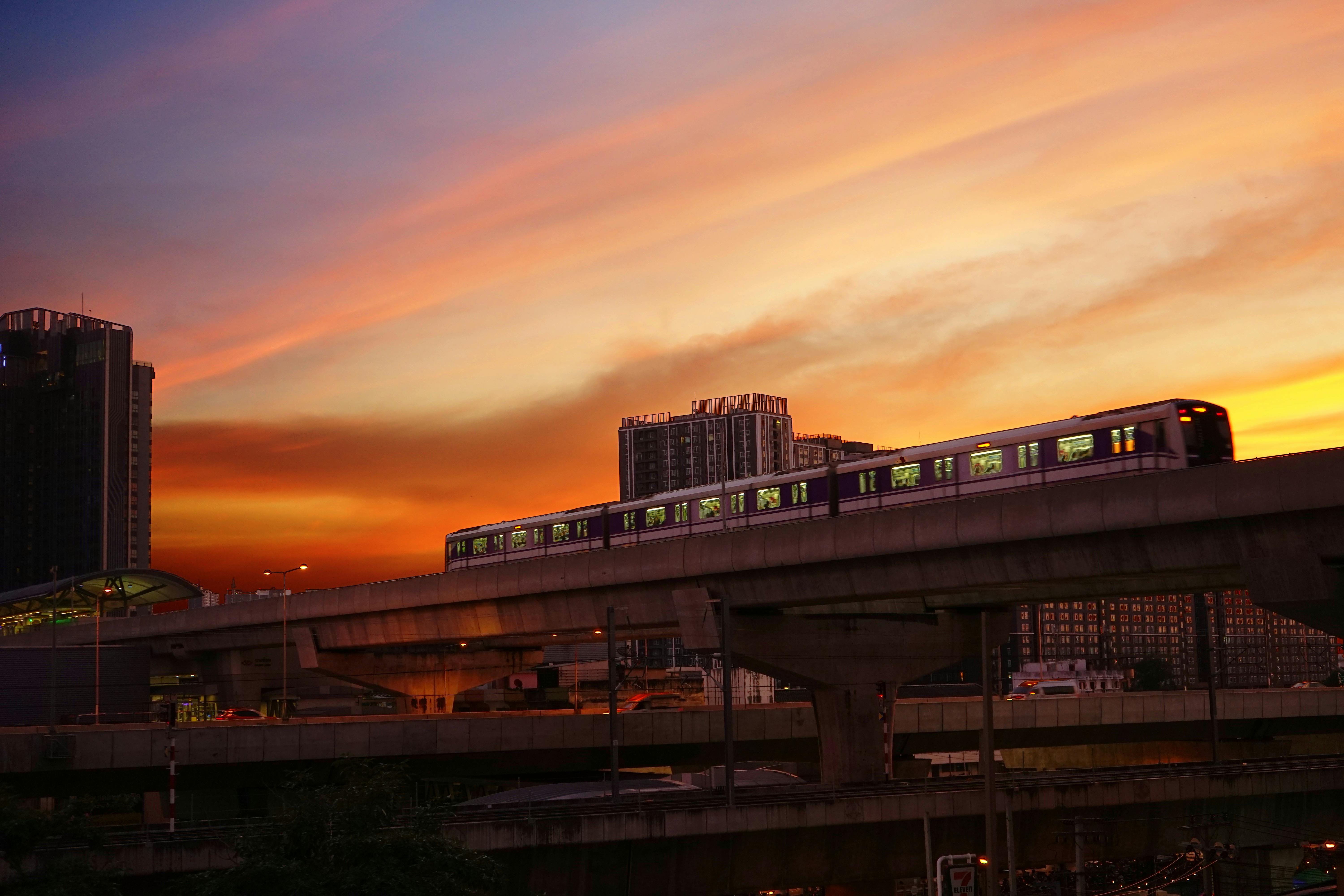 Elevated train against a dramatic sunset sky in Bangkok, representing urban transport in Thailand.