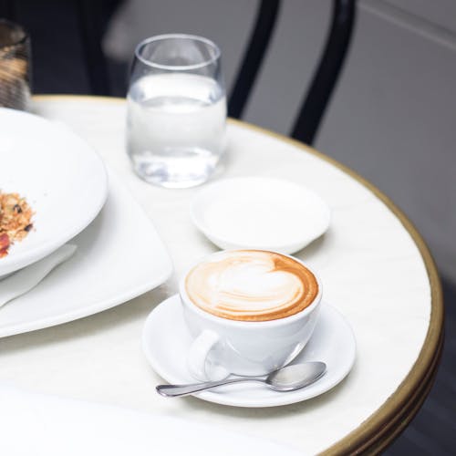Free Table with latte cup and glass of water in cafeteria Stock Photo