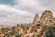 Majestic landscape of ancient houses carved out of volcanic rocky formations under cloudy sky