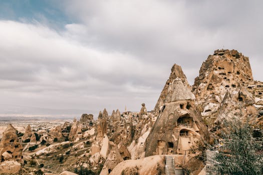 Majestic landscape of ancient houses carved out of volcanic rocky formations under cloudy sky