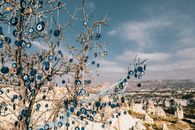 Amulets of blue glass reminding eye hanging on tree branches over are with volcanic formations