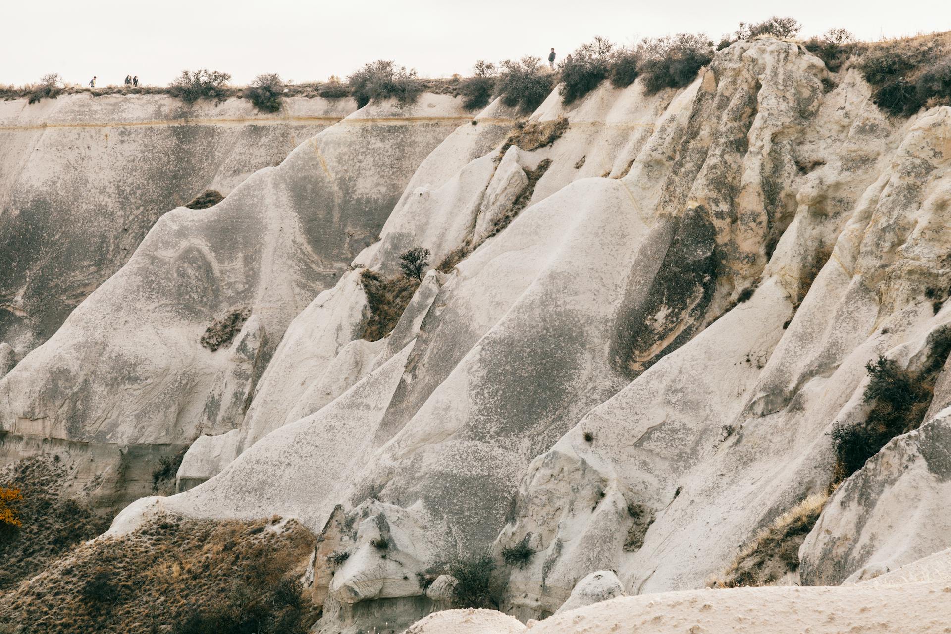 Massive rocky formation with dry plants on peak under overcast sky