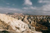 Various massive fairy chimney rock formations surrounded by cliffs against cloudy blue sky in Cappadocia