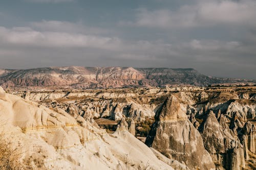 Wild valley with rough rocky cliffs under cloudy sky