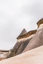 Sandy hills near stony uneven formations and plants in valley in Cappadocia region in Turkey in summer day under gray cloudy sky