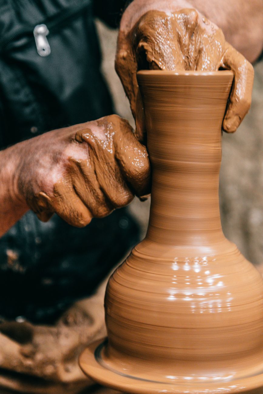 Craftsman modelling a clay vase on a pottery wheel