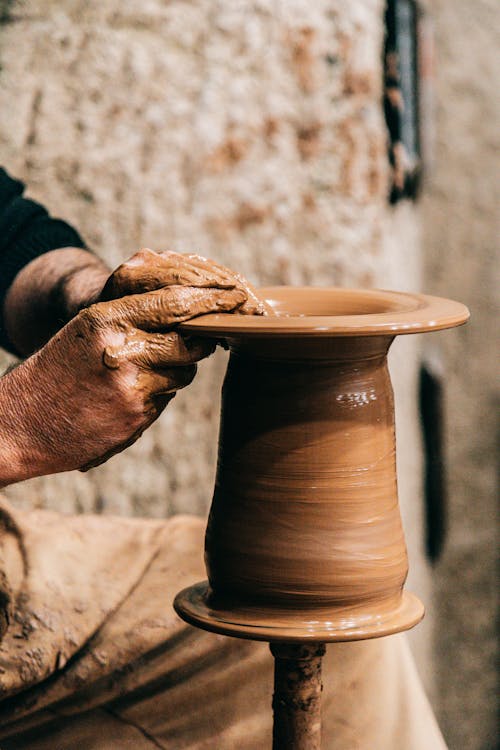 Man forming vase while working with clay
