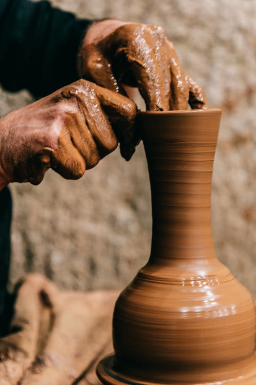 Man sculpting clay vase on pottery wheel