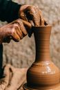 Man sculpting clay vase on pottery wheel