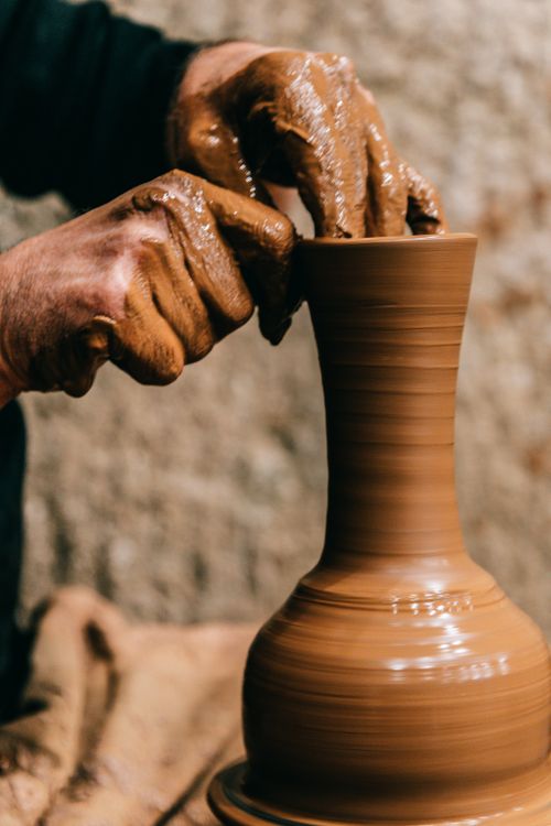 Free Crop anonymous male doing clay modeling while shaping fragile vase on blurred background Stock Photo