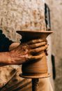 Crop anonymous male sculpting clay vase on professional pottery wheel on blurred background