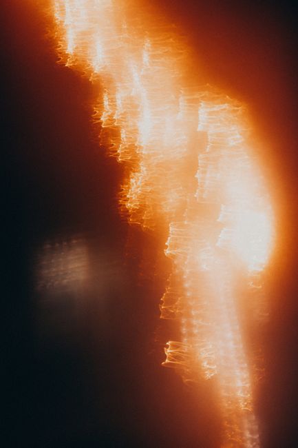 Abstract background of blurred bright orange lights burning on black backdrop in dark studio