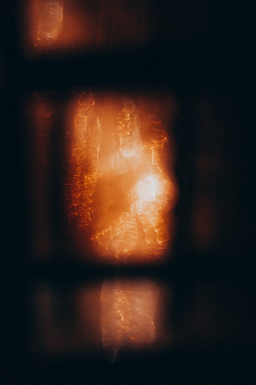 Abstract background of bright orange shining lights and sparkles behind blurred window in darkness