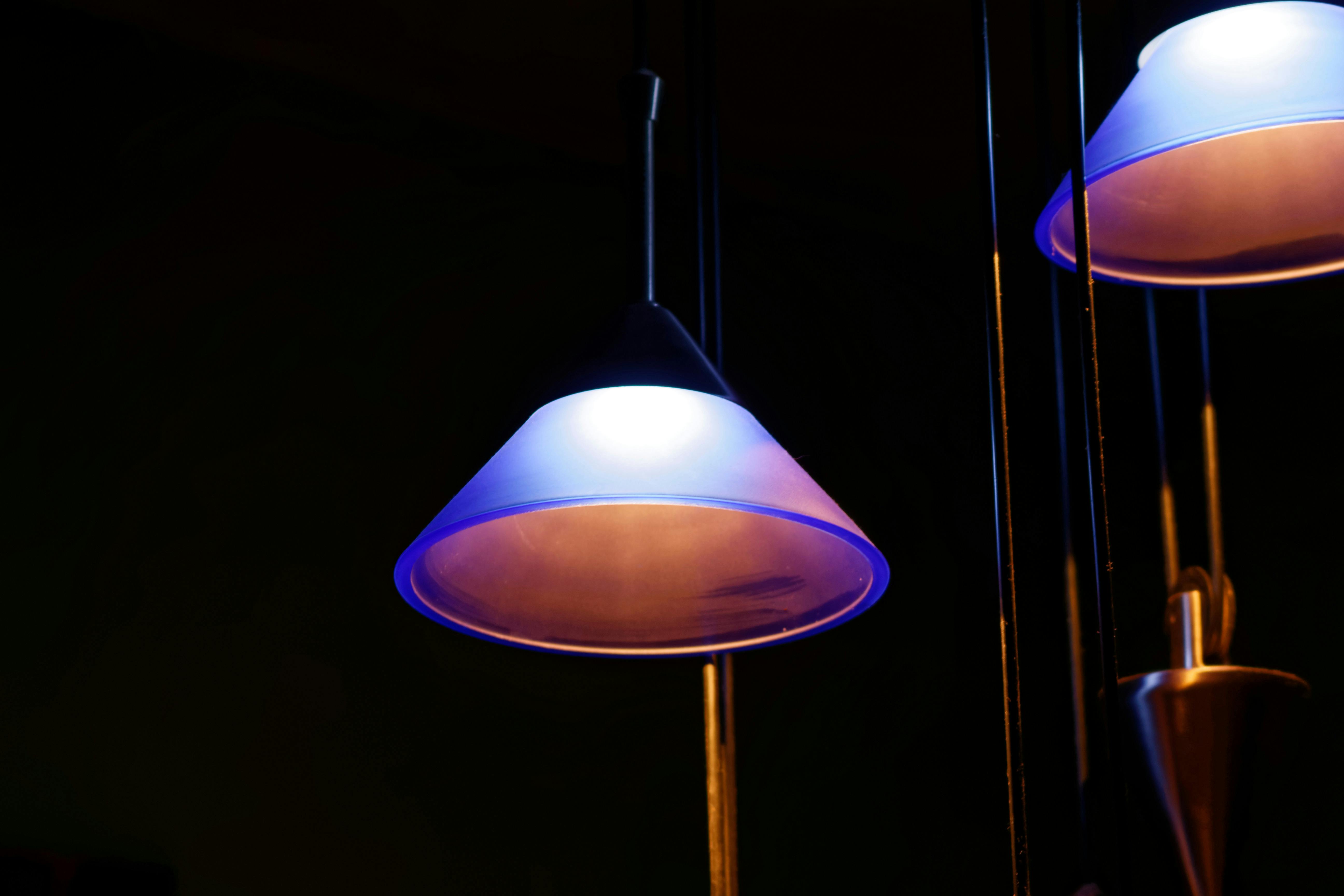 Contemporary pendant light with a soft blue glow against a dark interior, perfect for modern interior design.
