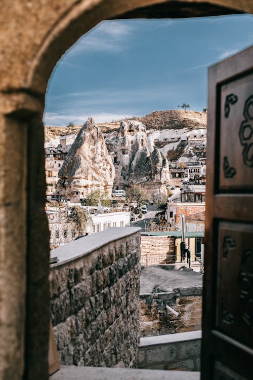 Free View from arched doorway on medieval Goreme town in Cappadocia among rocky cliffs Stock Photo