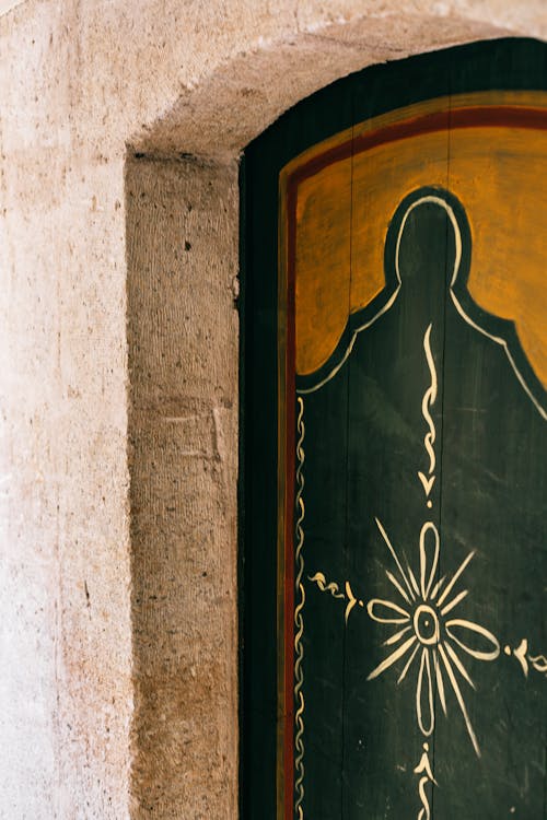 Free Entrance of ancient building with shabby stone wall and painted door with oriental patterns in arched doorway located on street Stock Photo