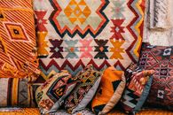 Colorful pillows with patterns placed on couch near abundance of ornamental oriental carpets on bazaar in old city on street