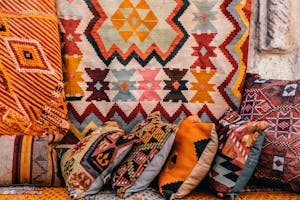 Colorful pillows with patterns placed on couch near abundance of ornamental oriental carpets on bazaar in old city on street