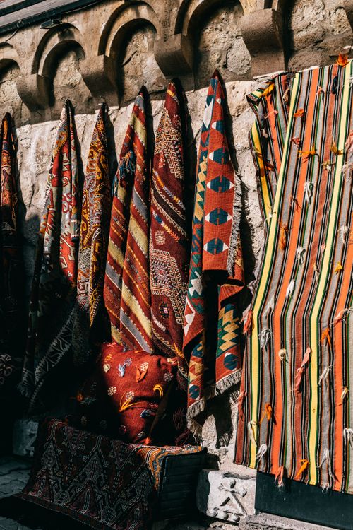 Free Abundance of bright carpets with pattern hanging on shabby wall in traditional oriental market on sunny street of old city Stock Photo