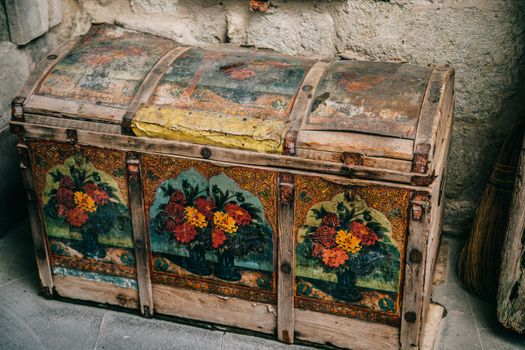 Ornate antique wooden chest with floral paintings in a historic setting.