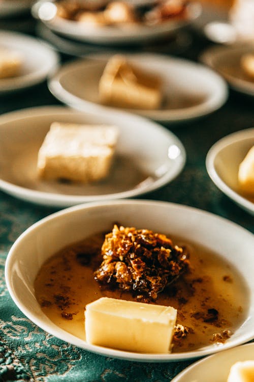 Haute cuisine with tasty meal served in white ceramic bowl on table with cloth against various dishes on blurred background in restaurant