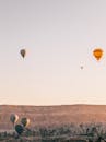 Picturesque scenery of air balloons floating over rocky formations of Cappadocia during festival at sunrise in Turkey