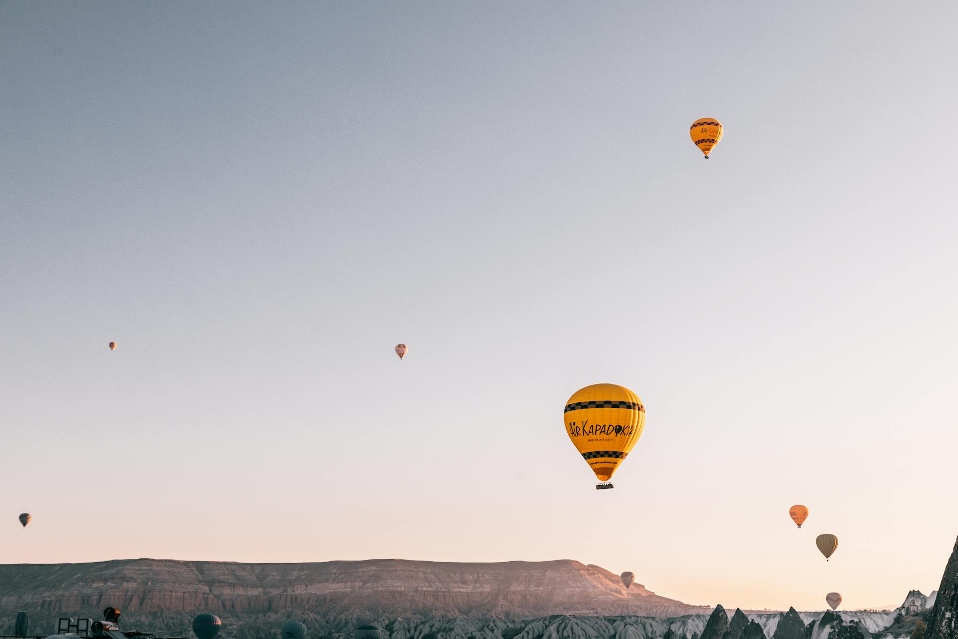 Hot air balloons flying over picturesque highlands at sunrise