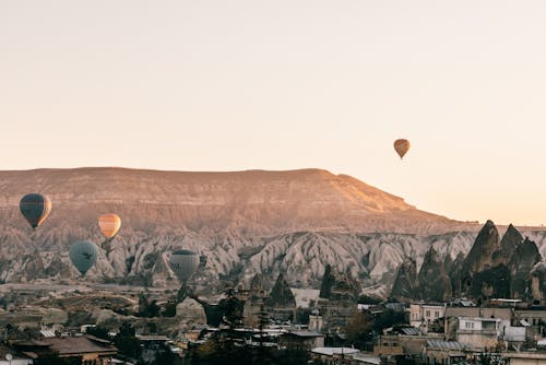 Picturesque scenery of hot air balloons racing over town placed among rocky formations in Cappadocia in Turkey at sunrise