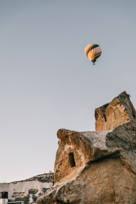 Picturesque scenery of rocky mountain placed in Cappadocia under cloudless blue sky with flying hot air balloon