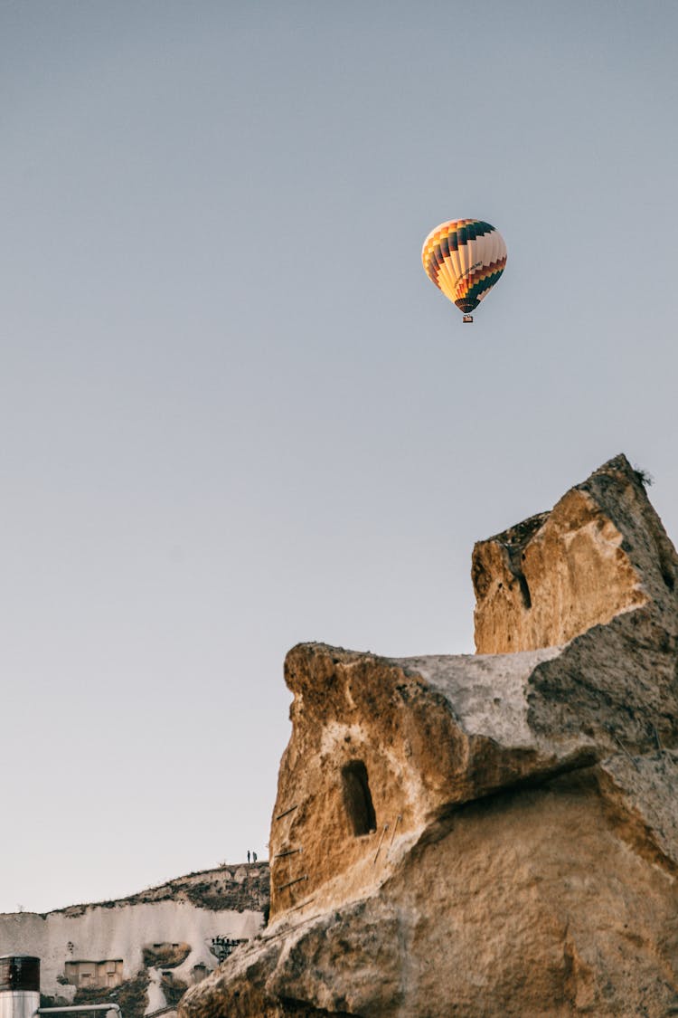 Multicolored Air Balloons Flying Over Rocky Formation In Daylight