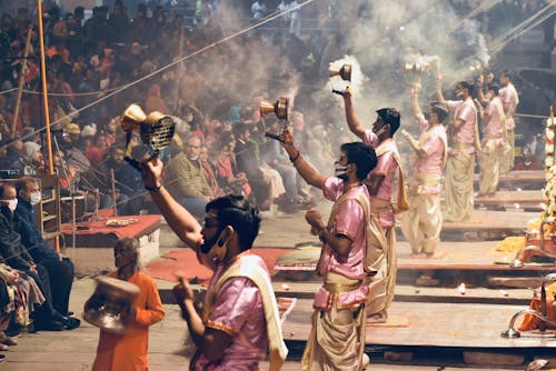 Men in Face Mask Spraying Incense for Crowd