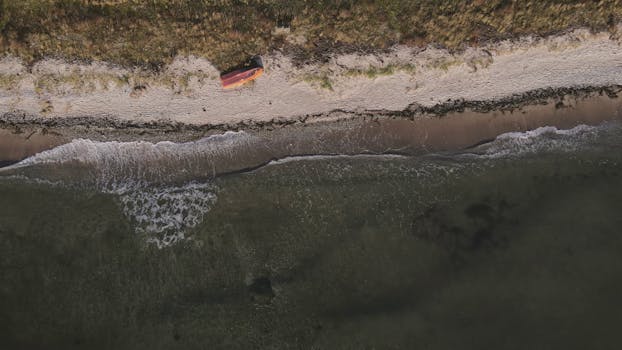A stunning aerial shot of a serene beach in Malmö, Sweden, showcasing clear waters and sandy shores.