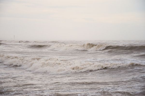 Heavy swell breaking under a grey sky — photo by photoGraph on Pexels