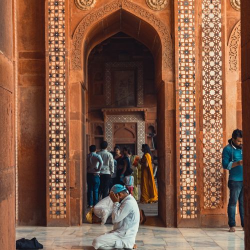 Free A man in traditional attire praying inside the historic Fatehpur Sikri Mosque, India. Stock Photo