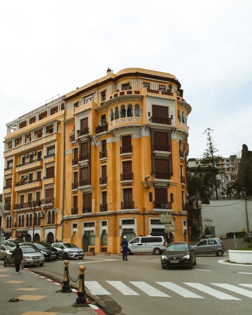 Free A vibrant yellow historic building located at a busy city intersection with approaching cars. Stock Photo