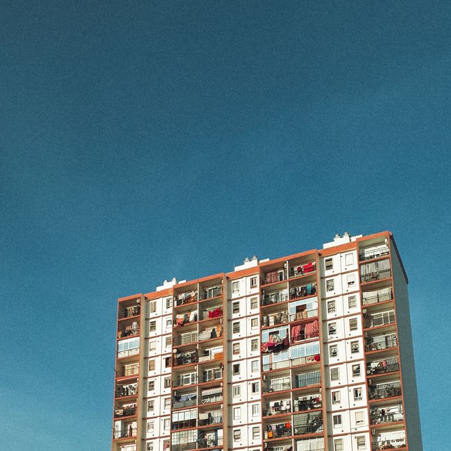 A striking image of a colorful apartment building against a clear blue sky, showcasing urban living.