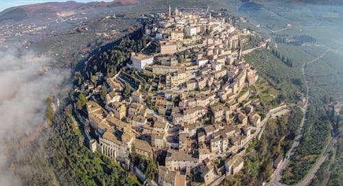 Free Drone view of medieval old San Marino city built on lush verdant hill in spacious valley Stock Photo