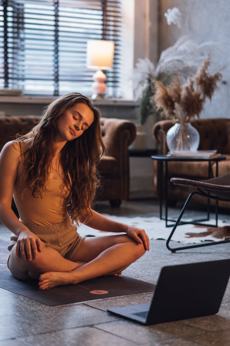 Woman In A Beige Top Doing Yoga Near Her Laptop