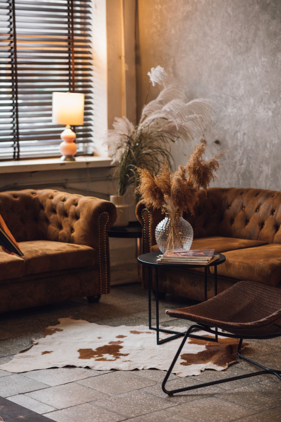 A warm showroom sitting area with a leather sofa and dried branches — photo by KoolShooters on Pexels
